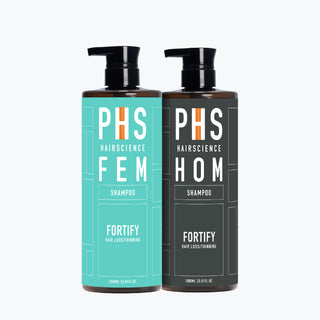 Two large pump bottles of PHS Hairscience shampoo, one labeled 'FEM' in teal color, and the other labeled 'HOM' in dark gray color.